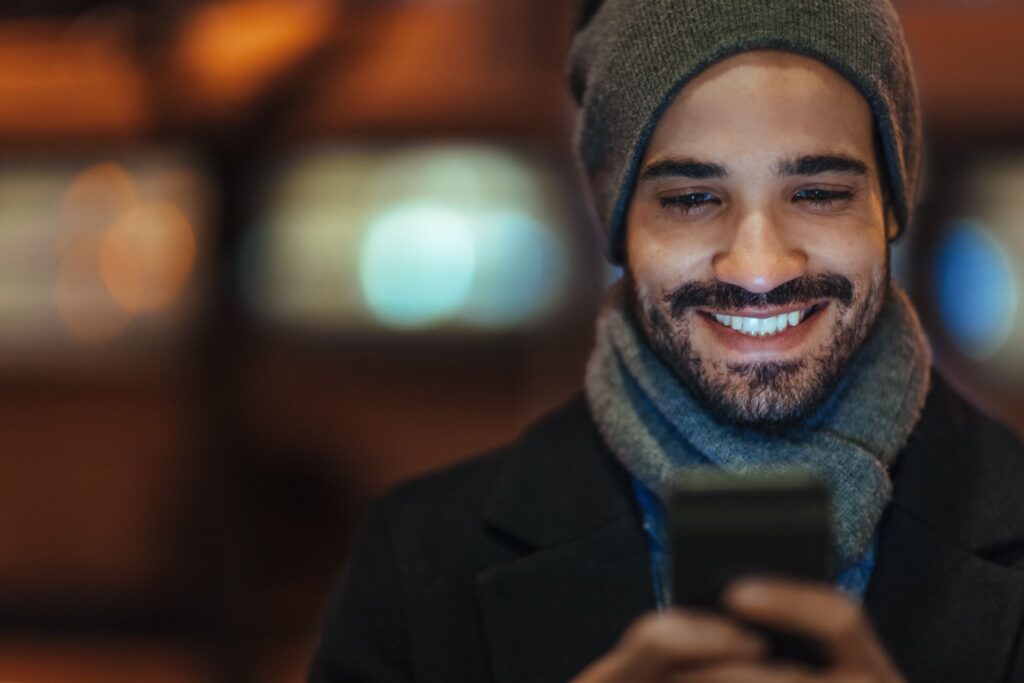 Young man using smartphone on city street at night