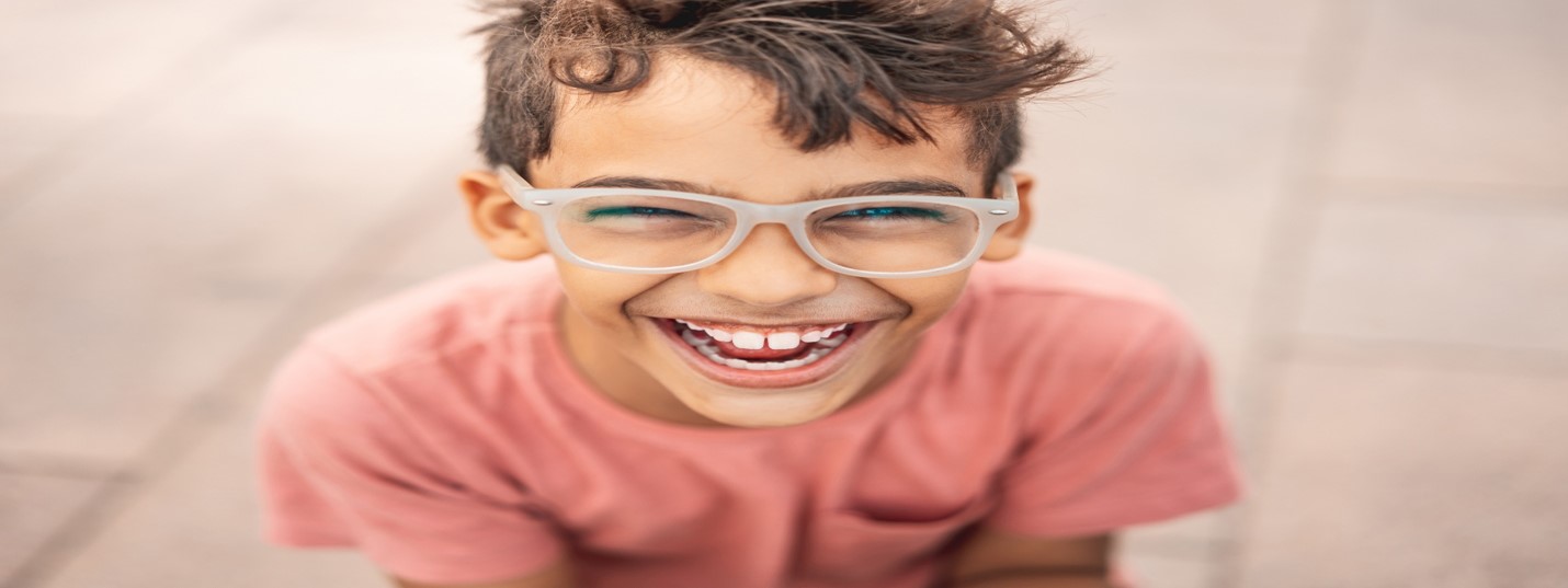 Head and shoulders of person with short hair wearing framed glasses and T-shirt, facing forwards and laughing