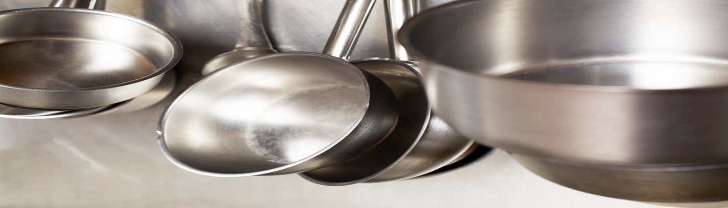 Close-up of stainless steel pans against stainless steel wall