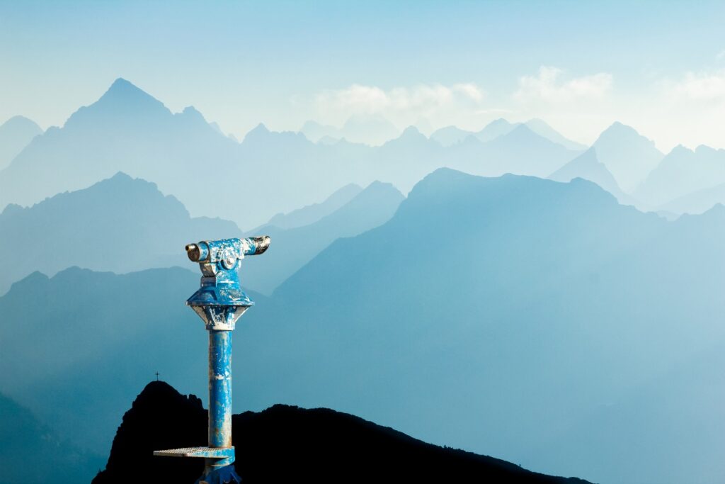 Binocular fixed on a top of mountains with other peaks