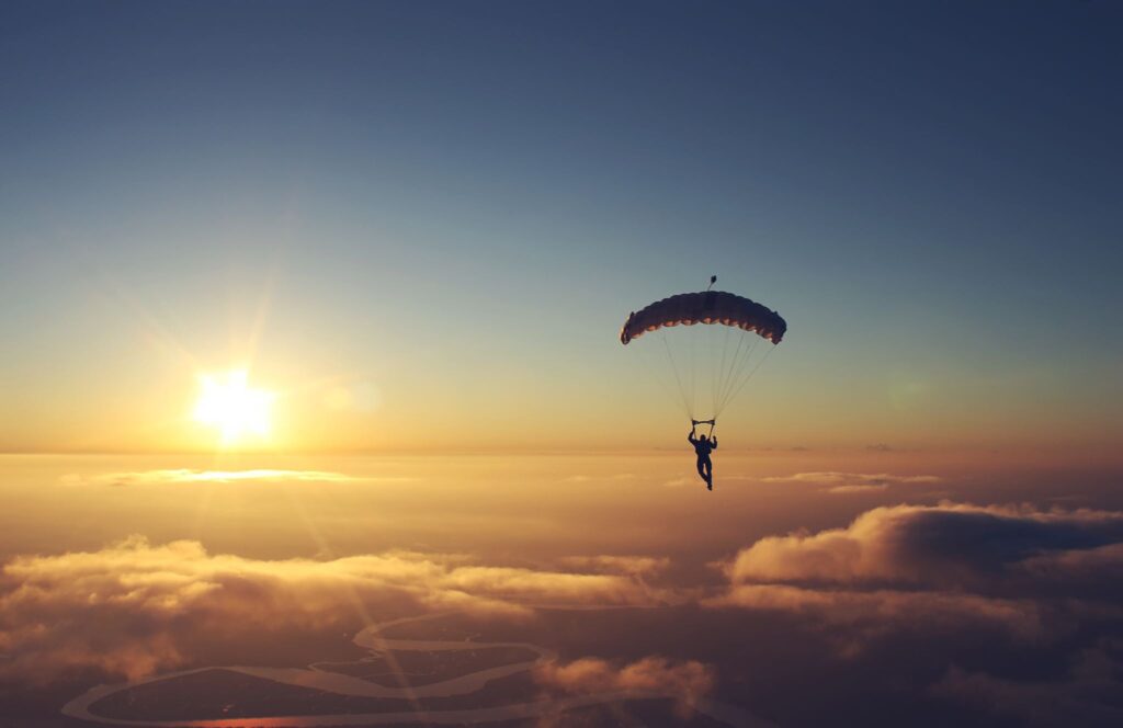 A scenic view of the sky with a person on a parachute seemingly approaching the sunset