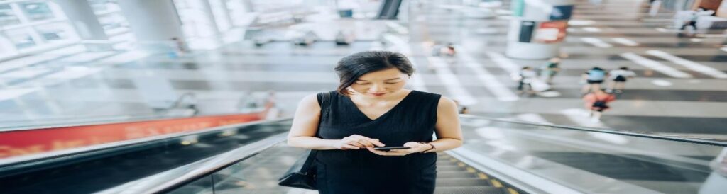 Businesswoman reading emails on escalator
