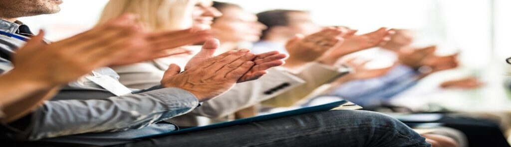 Row of seated people clapping hands at work event