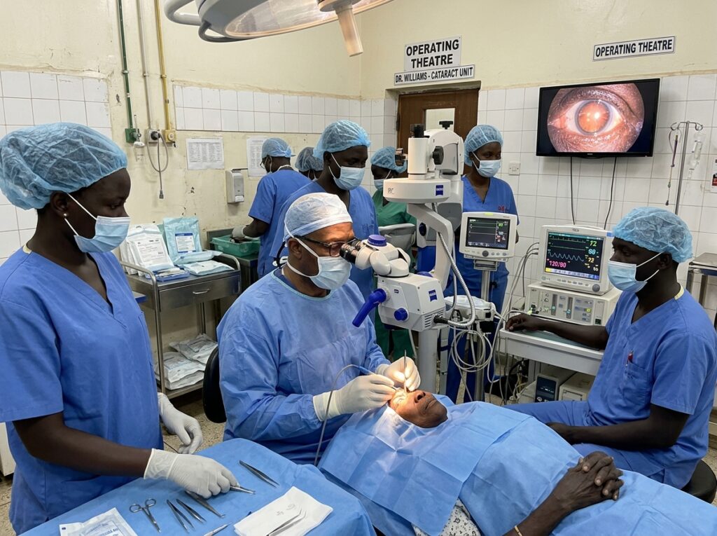 Dr. Lloyd B. Williams, a Black man in surgical attire, performing cataract surgery in a South Sudanese operating room, surrounded by a diverse team of local medical staff, with focused precision and care.